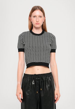 Svart og hvit cropped strikket topp med geometrisk mønster, korte ermer og ribbestrikket halslinning. Matchet med svarte, løse bukser.