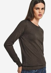 Brun långärmad sweatshirt med en figurnära design, rund halsringning och ribbade ärmslut, tillverkad av ett mjukt och glatt tyg.