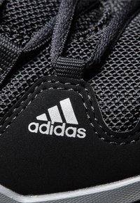 Černá atletická bota s vrchní částí z síťoviny a semišovými akcenty, černými tkaničkami a výrazným stříbrným logem Adidas na boku.