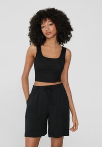 Top corto a coste nera con scollatura quadrata abbinato a pantaloni corti neri con coulisse e tasche laterali, entrambi realizzati in tessuto morbido.