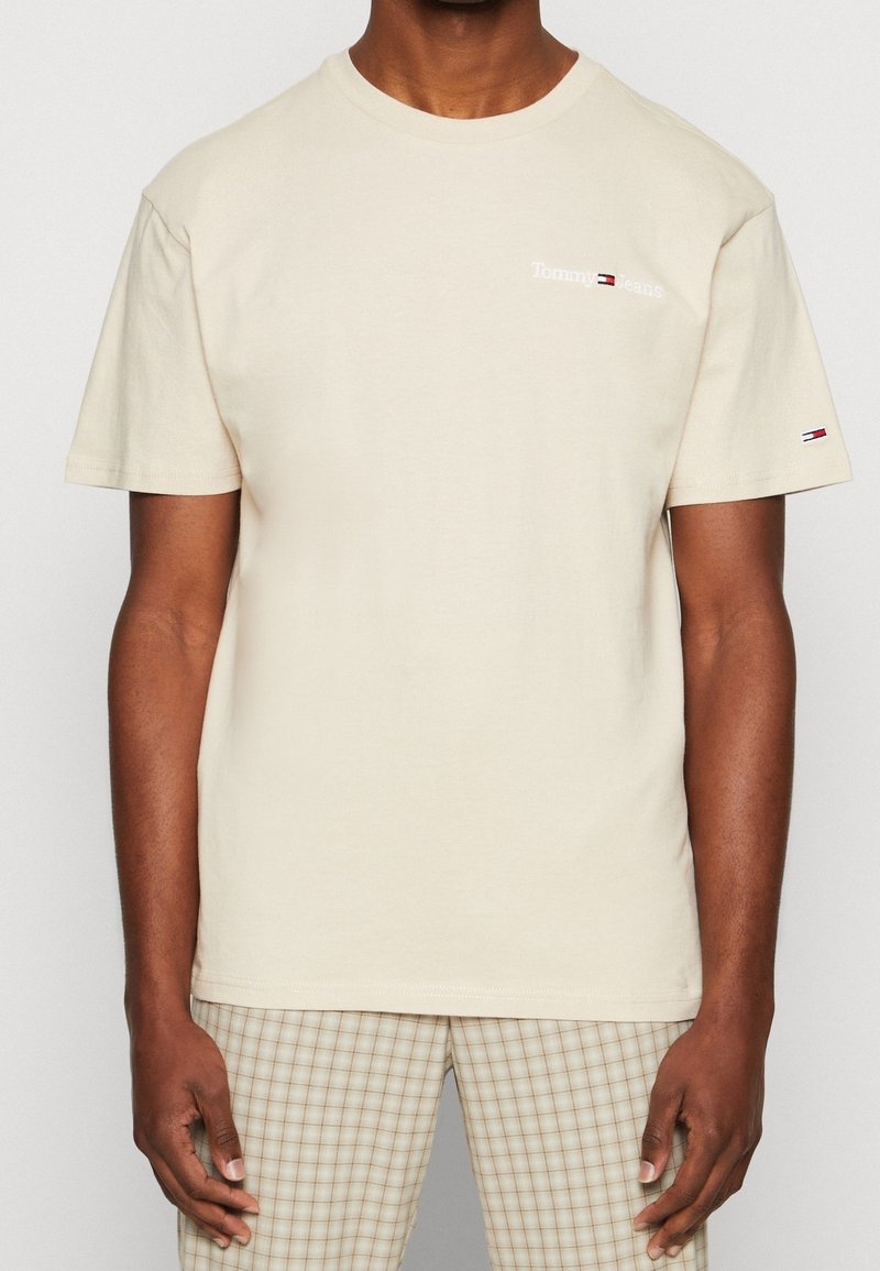 Beige cotton t-shirt with short sleeves and a round neckline, featuring a small white embroidered "Tommy Jeans" logo on the chest.