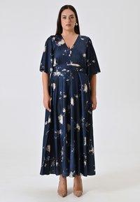 Langes, marineblaues Kleid aus seidig glänzendem Stoff mit floralem Muster in Creme- und hellen Farbtönen. Es hat einen V-Ausschnitt, kurze Ärmel und eine taillierte Passform.