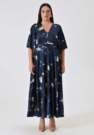Robe longue bleu marine en tissu satiné avec un motif floral en crème et teintes claires. Comprend un décolleté en V, des manches courtes et une taille cintrée.