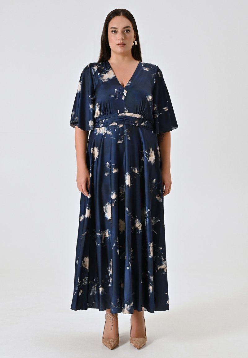 Lange navy blauwe jurk van zijdeachtige stof met een bloemenpatroon in crème en lichte tinten. Heeft een V-hals, korte mouwen en een getailleerde taille.