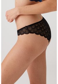 Zwarte kantpanty's met geschulpte randen, voorzien van een bloemenpatroon. Zachte textuur en rekbaar ontwerp, ontworpen voor comfort en stijl.