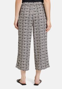 Czarne i beżowe szerokie spodnie o wzorze geometrycznym z teksturowanymi akcentami oraz elastycznym pasem dla komfortu.