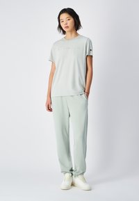 T-shirt en coton vert clair avec le logo "Champion" en relief ; assorti avec un pantalon de jogging, doté d'une taille élastique et de poches latérales.