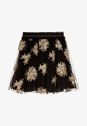 Jupe en tulle noire avec broderie florale dorée, taille froncée avec élastique, longueur au genou et texture superposée avec un voile transparent.
