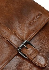 Borsa a tracolla in pelle marrone con superficie texture, dotata di una fibbia in metallo e dettaglio del logo impressa.