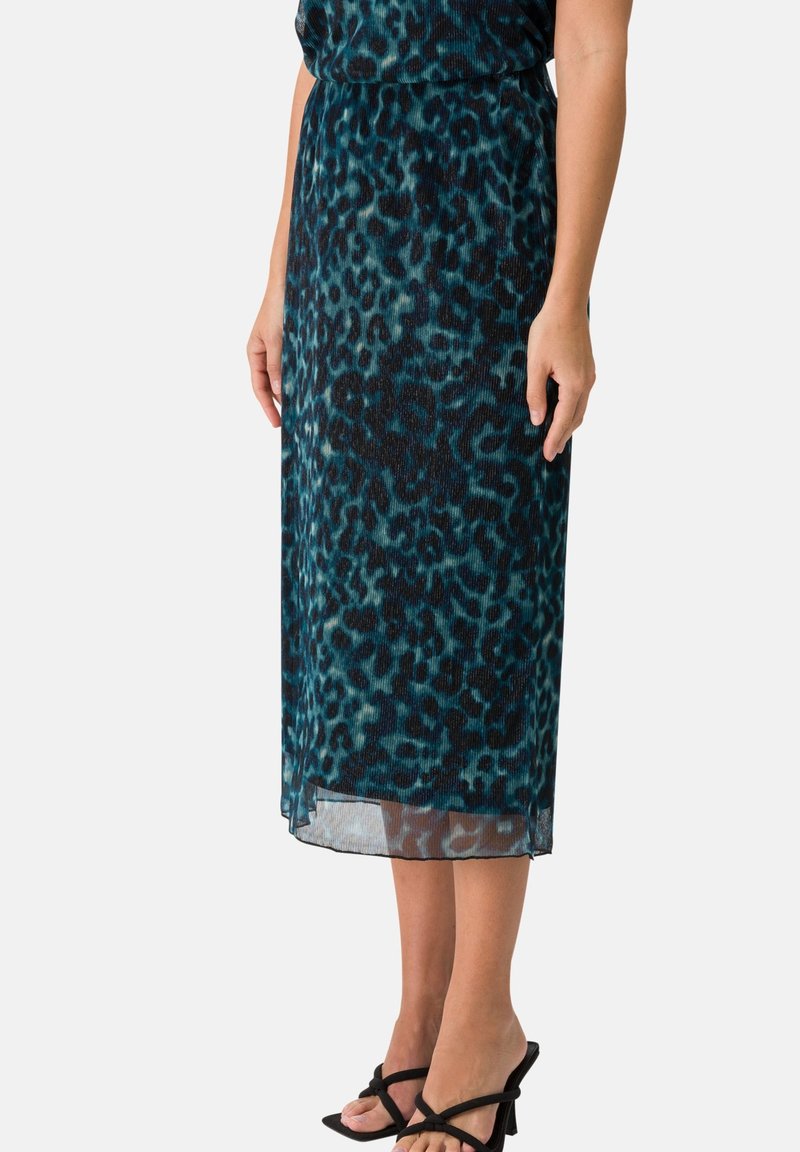 Una falda midi con estampado de leopardo en color verde azulado, hecha de tejido ligero, que presenta una cintura ajustada y un dobladillo que termina justo por encima de los tobillos.
