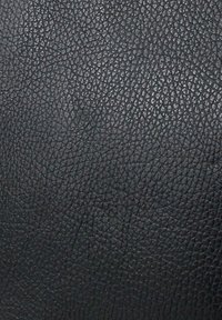 Gros plan d'une surface en cuir noir texturé avec un petit motif irrégulier semblable à des cailloux et des reflets de lumière subtils.