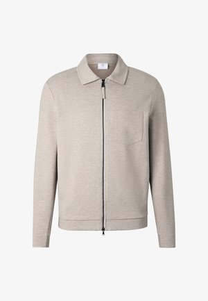 Jasnobeżowa kurtka na zamek z kołnierzem, długimi rękawami i pojedynczą kieszenią na piersi, prezentowana na białym tle.