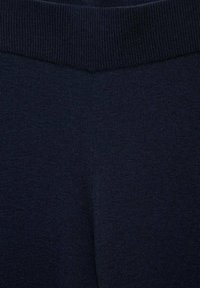 Primo piano di un tessuto lavorato a maglia a coste di un blu navy scuro che mostra la vita e il motivo delle cuciture texture.