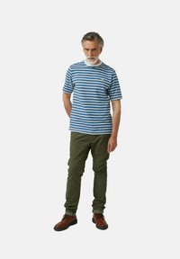 Camiseta de rayas azul y blanca de manga corta con un pequeño logo, combinada con pantalones verdes oliva y zapatos marrones con cordones.