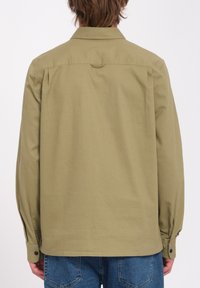 Khaki puuvillainen pitkähiha tunikapaita klassisella kauluksella, napilliset hihansuut ja sileä pinta, suoran leikkauksen ja takakiilatyylin yksityiskohdalla.