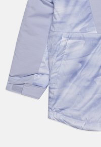 Light blue jacket with a tie-dye pattern on the body and solid textured sleeves. Features a Velcro cuff, showcasing durability and style.