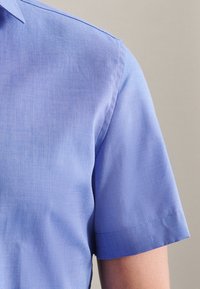 Koszula z krótkim rękawem w jasnoniebieskim kolorze, wykonana z gładkiej tkaniny z delikatną prążkowaną fakturą oraz starannym wykończeniem kołnierzyka i rękawów.