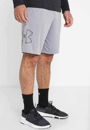 Graue Sportshorts mit elastischem Bund und einem schwarzen Under Armour-Logo am linken Bein, kombiniert mit schwarzen Socken und Sportschuhen.