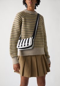 Borsa a tracolla a righe bianche e nere con bordi arrotondati, caratterizzata da un logo del marchio ben visibile. La borsa è realizzata in tessuto liscio e ha una tracolla regolabile.