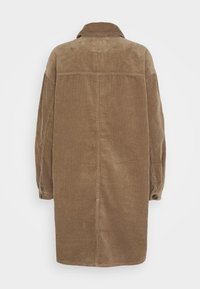Veste en velours côtelé marron avec col, manches longues et deux boutons aux poignets. Le tissu présente une texture côtelée verticale.