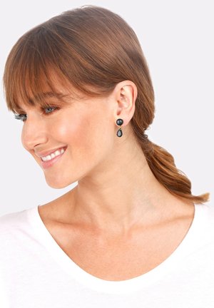 Boucles d'oreilles noires en forme de puces avec un sommet rond et un design pendulaire, mettant en avant un accent en goutte d'eau. Texture lisse et finition brillante.