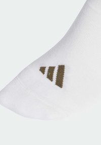 Calcetín deportivo blanco con tejido texturizado. Presenta un logo triangular marrón en la zona del tobillo. Acabado suave y diseño ajustado.
