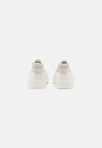 Witte leren sneakers met een gladde textuur, afgeronde vorm en een laag model. Contraststiksels en minimale branding op de hiel.