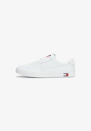 Zapatilla baja blanca hecha de cuero liso, con un cuello acolchado, cordones planos y un pequeño parche de logo con acentos rojos y azules en el costado.