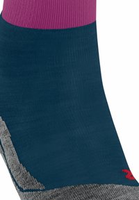 Socken mit lila Bündchen, dunkelblauem Körper, grauem Fersen- und Zehenbereich, zieren ein kleines rotes Logo im Zehenbereich.