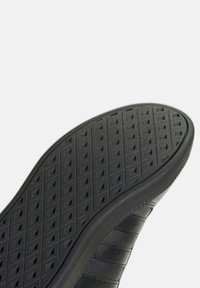 Zwarte sneakerzool met een gestructureerd, patroonoppervlak met driehoekige vormen en een gladde rand; gemaakt van rubber en synthetische materialen.