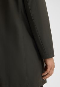 Cappotto verde scuro con maniche lunghe e una texture liscia. Caratterizzato da linee pulite, cuciture sottili e una silhouette aderente in vita.