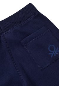 Granatowe spodnie dresowe z prążkowanym pasem, z tylną kieszenią i wzornictwem na tkaninie. Miękka faktura i swobodny styl.