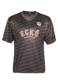 Musta lyhythihainen T-paita, jossa on all-over-logokuvio, V-pääntie ja punainen "ECKŌ unlimited" -teksti etupuolella pienen embleemin kanssa.