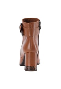 Braune Leder-Stiefelette mit einem hohen Blockabsatz, seitlichem Reißverschluss und einer dekorativen, runden Schnalle am äußeren Schaft. Strukturiertes Absatz-Detail.