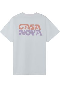 Balta kokvilnas T-kreklu ar lielu, krāsainu tekstu uz muguras, kas lasāms "CASA NOVA" oranžā un violetā krāsā, ar brīvu griezumu.