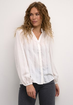 White button-up shirt with vertical stripes, slightly sheer fabric, gathered sleeves, and a mandarin collar. Paired with dark jeans.