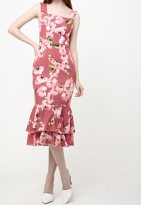 Figurbetontes, rosa Blütenkleid mit quadratischem Ausschnitt und ausgestelltem Rüschensaum. Hergestellt aus glattem Stoff, der große Orchideen-Muster und grüne Akzente aufweist.