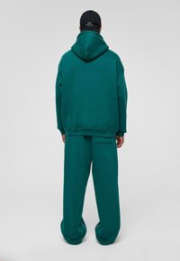 Teal hoodie met een voorzak en bijpassende losse sweatpants. Zachte stof met een gladde textuur, oversized silhouet en een casual ontwerp.
