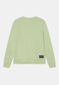 Zelená mikina s dlouhými rukávy, žebrovanými manžetami a lemem a texturovaným povrchem. Obsahuje černou nášivku na levé straně.