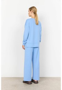 Felpa oversize azzurro chiaro e pantaloni a gamba larga coordinati, realizzati in materiale morbido, con una vestibilità rilassata e dettagli di cucitura sottili.