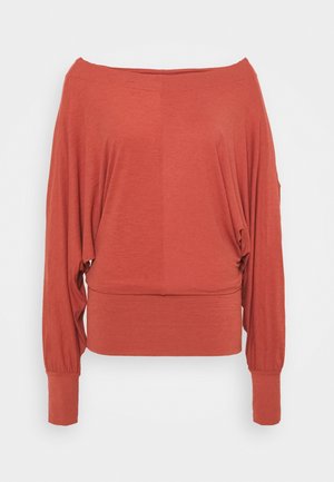 Top arancione ruggine con scollatura a barca, maniche lunghe a pipistrello larghe, polsini e fascia in vita aderenti.