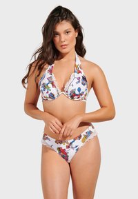 Bikini-set med vit bakgrund, färgglad blommönster, volangkanter, halterneck topp och tygklädda trosor.