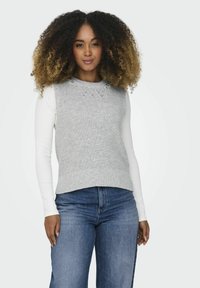 Grijze gebreide trui met een kraalversierde halslijn, gedragen over een witte lange mouwen top. Gemaakt in combinatie met blauwe denim jeans met een rechte pasvorm.