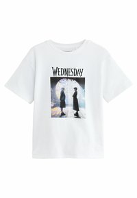 Vit t-shirt med en grafisk tryck av två figurer med texten "WEDNESDAY" ovanför, placerad i en färgglad, spindelnätliknande miljö.