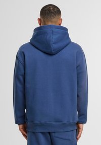 Blauwe hoodie met een relaxed fit, gemaakt van zachte stof. Voorzien van ribgebreide manchetten en een zoom, met een naadloze achterkant en capuchon.