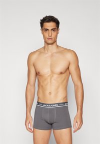 Graue Herren-Boxershorts mit enger Passform, ausgestattet mit einem schwarzen Bund mit dem "JACK & JONES"-Logo, glattem Stoff und genähten Nähten.