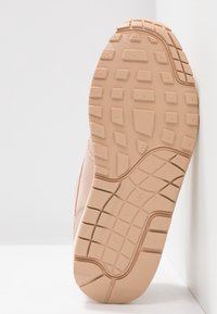 Světlé růžové sportovní podrážky se strukturovaným gumovým podrážím s mřížkovým vzorem pro lepší trakci a odolnost.