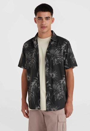 Short-sleeve black shirt with gray floral pattern, button-up design, worn over a light beige t-shirt, paired with light pink cargo shorts.