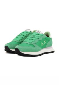 Sneakers sportive verdi con tomaia in suede e tessuto, dettagli bianchi, lacci piatti, suola ammortizzata e testo "LE RAGAZZE CORSO PIÙ VELOCE" sulla linguetta.