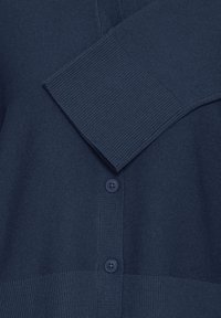 Cardigan tricotat bleumarin, cu un corp texturat, manșete cu revenire și două nasturi în față. Material moale, cu un aspect confortabil.